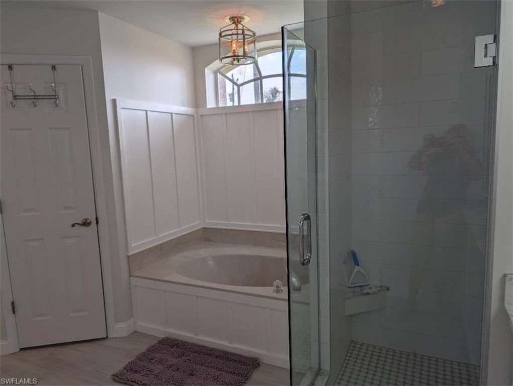 Bathroom featuring a shower stall, a garden tub, and wood finished floors