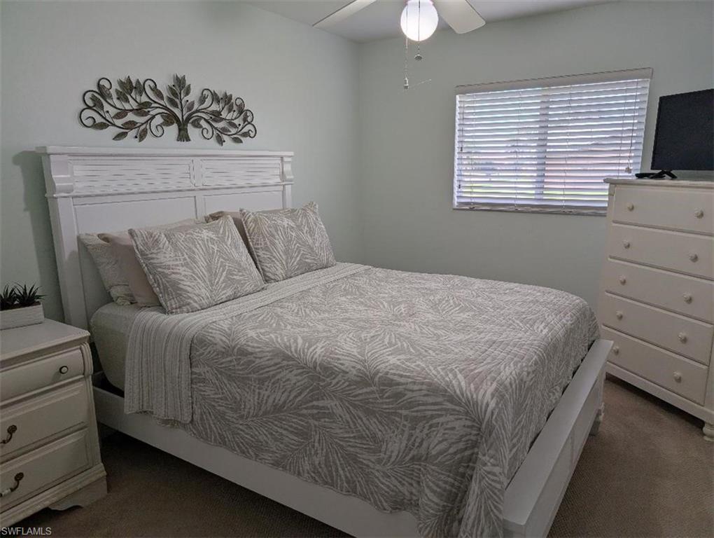 Carpeted bedroom with a ceiling fan