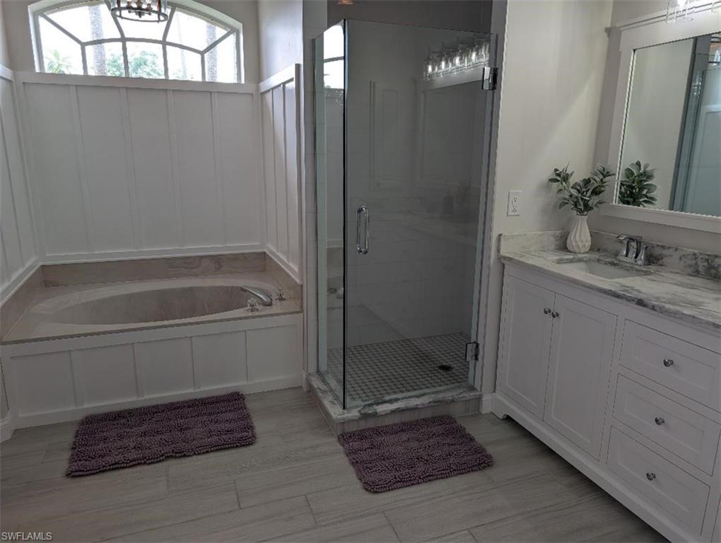 Full bathroom featuring a bath, a shower stall, and vanity