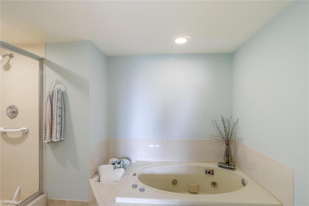 Built-in jetted tub with tiled surround, adjacent to a glass-enclosed shower separate.