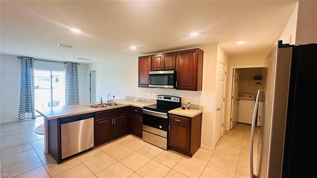 Kitchen featuring dark wood-finish cabinetry, light speckled countertops, and stainless steel appliances
