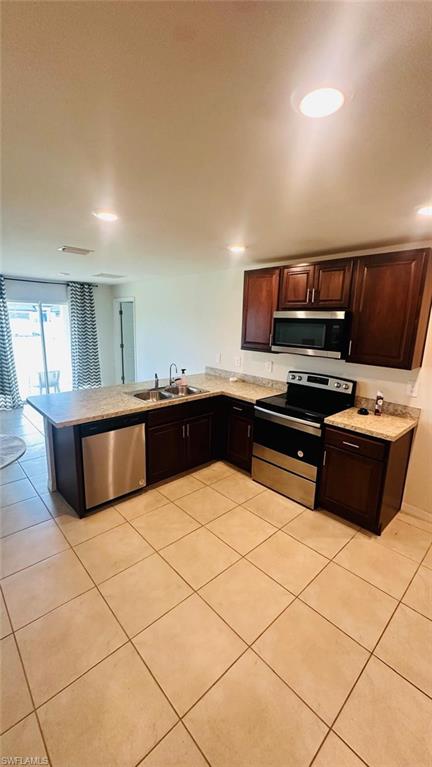 Kitchen featuring dark wood cabinetry, light-toned countertops, stainless steel appliances, and recessed lighting
