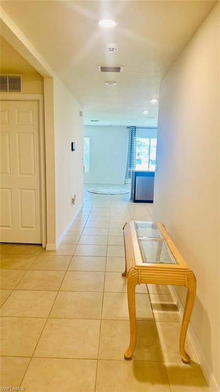 Tiled hallway featuring recessed lighting and a solid core interior door