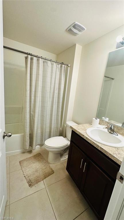 Bathroom featuring a full tub/shower combination, dark wood-finish vanity with a laminate countertop, and tile flooring