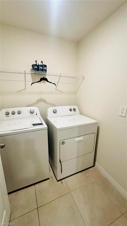 Dedicated laundry area featuring a washer and dryer, tiled flooring, and a wire shelving unit