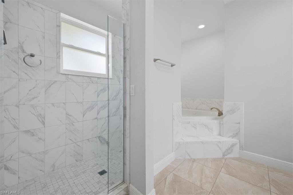 Spacious bathroom featuring a glass-enclosed shower with white marble-patterned tile and a mosaic tile floor