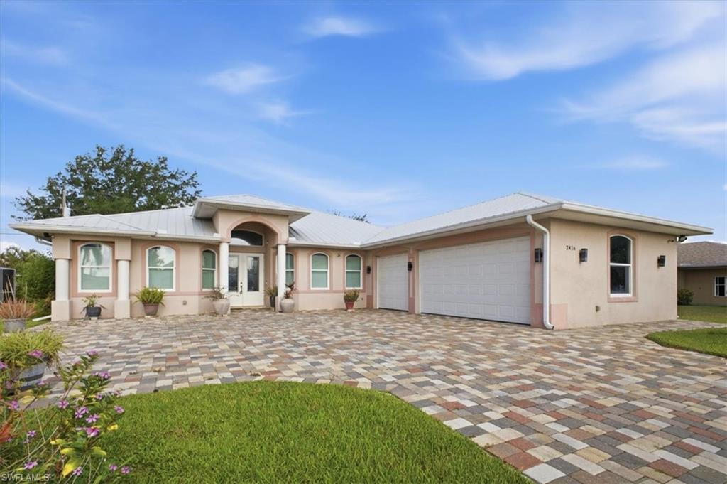 Stucco exterior residence featuring a metal roof, an arched entryway, and multiple arched windows