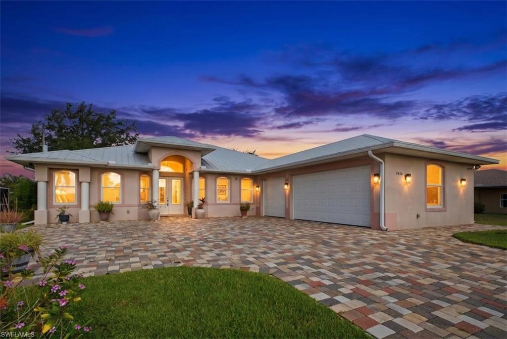 Stucco exterior featuring an arched portico entry with double doors, multiple arched windows, and a multi-car garage
