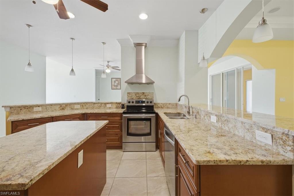 Kitchen featuring granite countertops, wood cabinetry, stainless steel appliances, recessed lighting, and tile flooring
