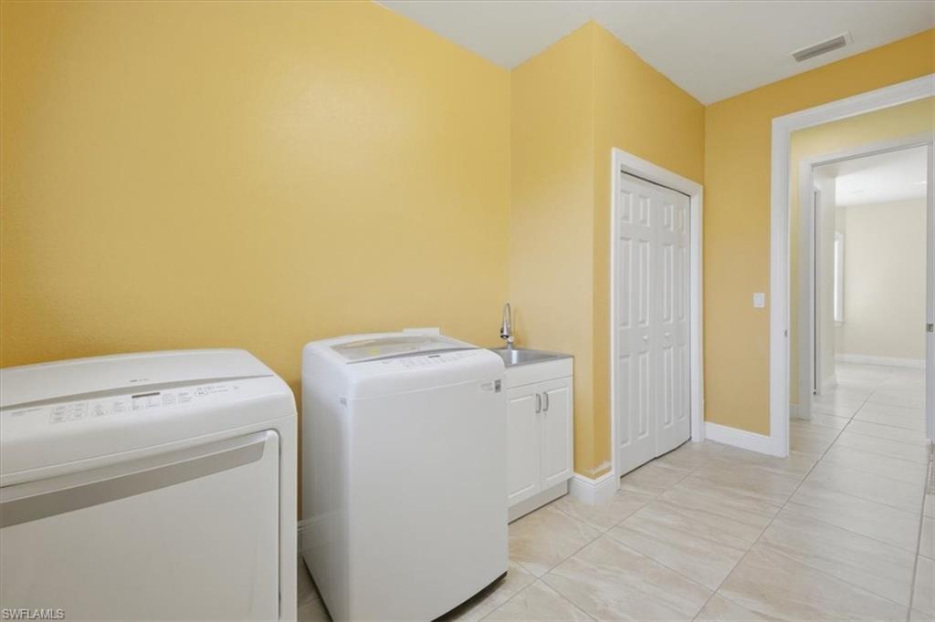 Laundry room featuring tile flooring, a utility sink with a white cabinet, and a bi-fold closet door