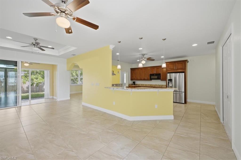 Open-concept living area with large format tile flooring, a tray ceiling, and sliding glass doors