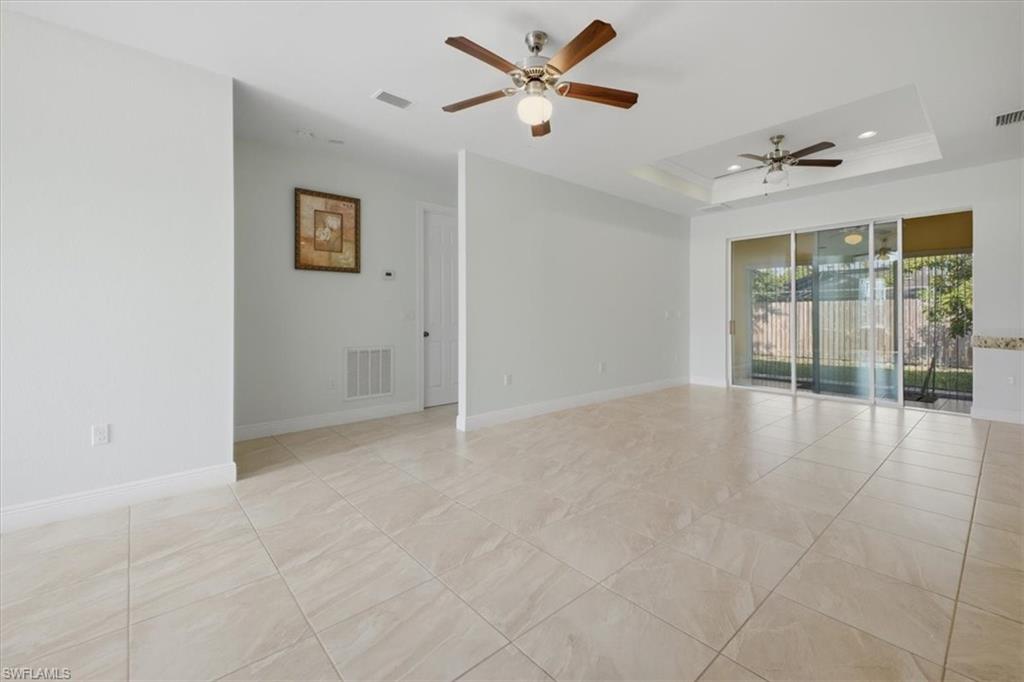Spacious room featuring neutral tile flooring, light-toned walls, and multiple ceiling fans