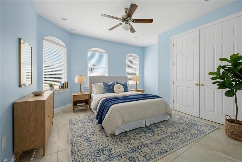 Recessed lighting illuminates this room featuring light blue walls, arched windows with blinds, and tile flooring