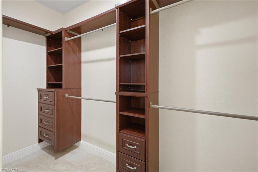 Built-in wood-finish closet system featuring shelving, drawers, and hanging rods