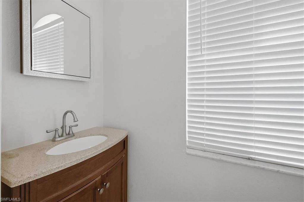 Vanity featuring a curved wood-finish cabinet, speckled countertop, and integrated oval sink
