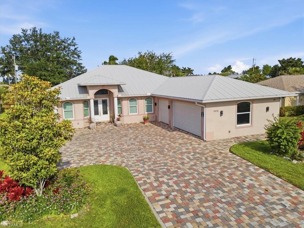 Contemporary stucco exterior with a metal roof and a paver driveway