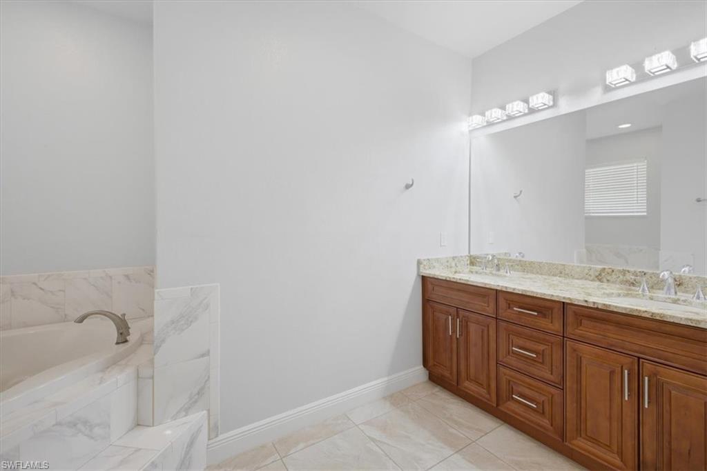 Dual vanity with a stone countertop and wood cabinetry, featuring individual basin sinks and chrome faucets