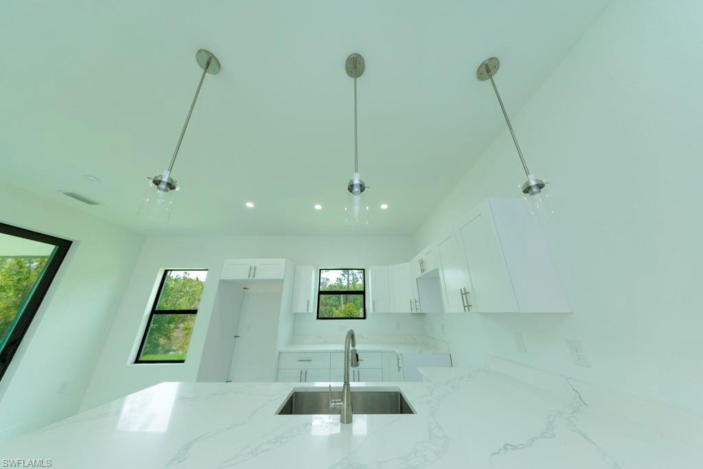 Kitchen island featuring a stainless steel undermount sink, a gooseneck faucet, and a light-colored countertop with subtle veining