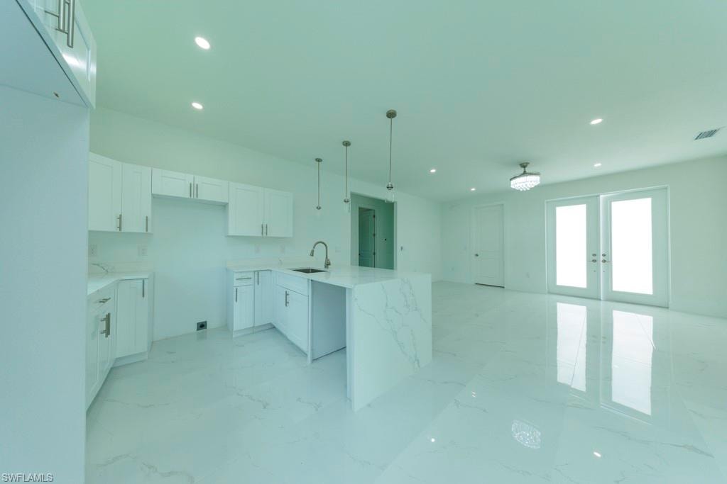 Modern kitchen with white cabinetry and an oversized island featuring a waterfall countertop