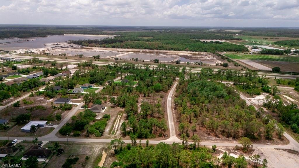 Aerial perspective showcasing a residential area with established homes, undeveloped land parcels, and mature tree cover
