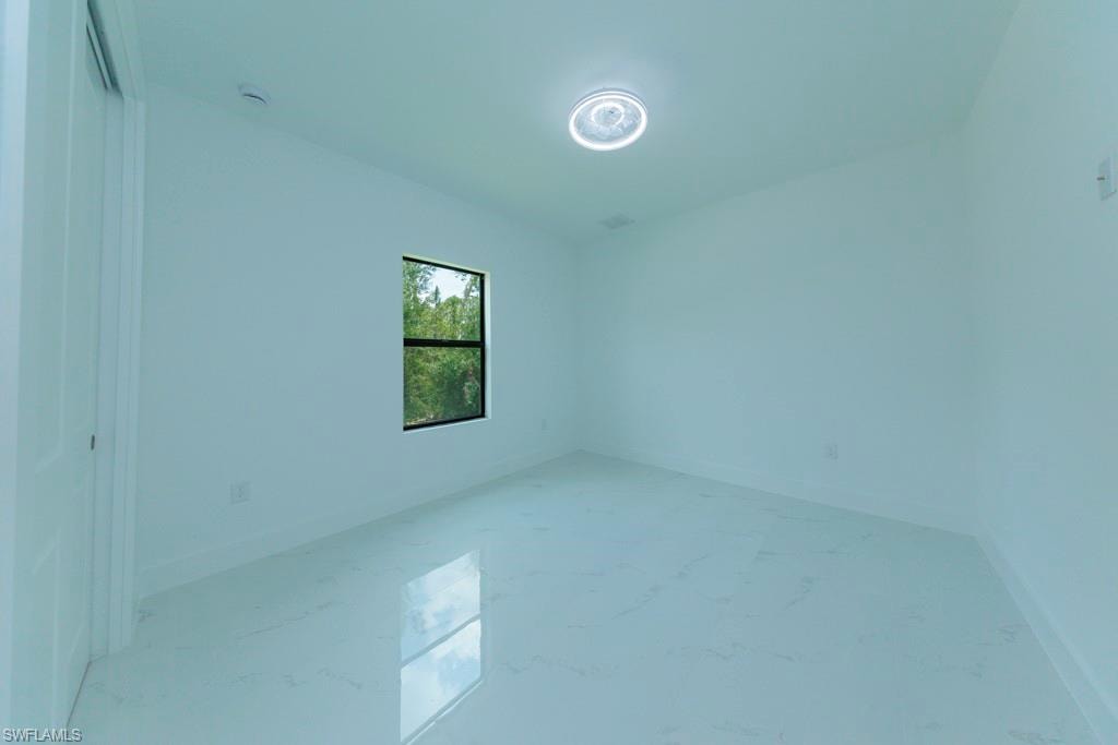 Bright interior space featuring a window with black trim, a contemporary ceiling light fixture, and white walls