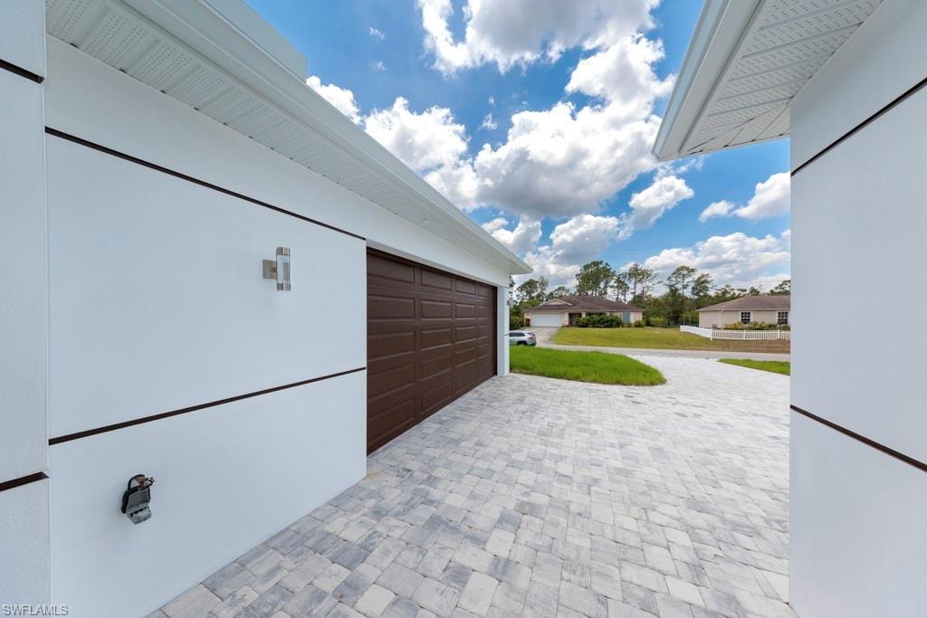 Modern exterior featuring white siding with black trim accents and a brown garage door