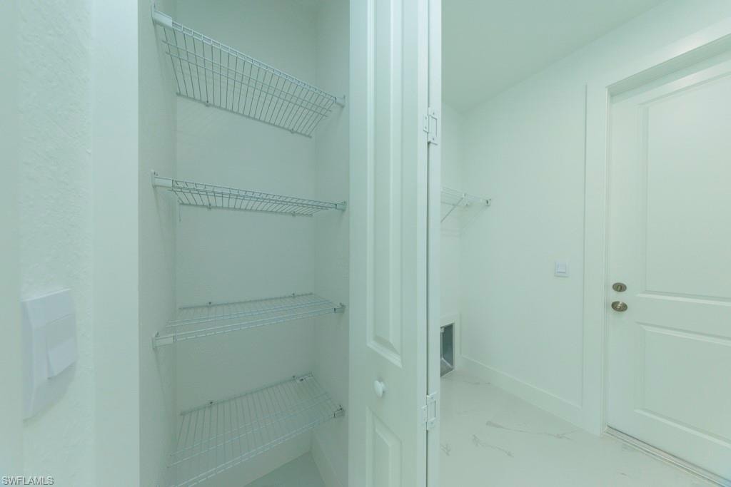 Utility space featuring wire shelving, a paneled door, and light-toned flooring