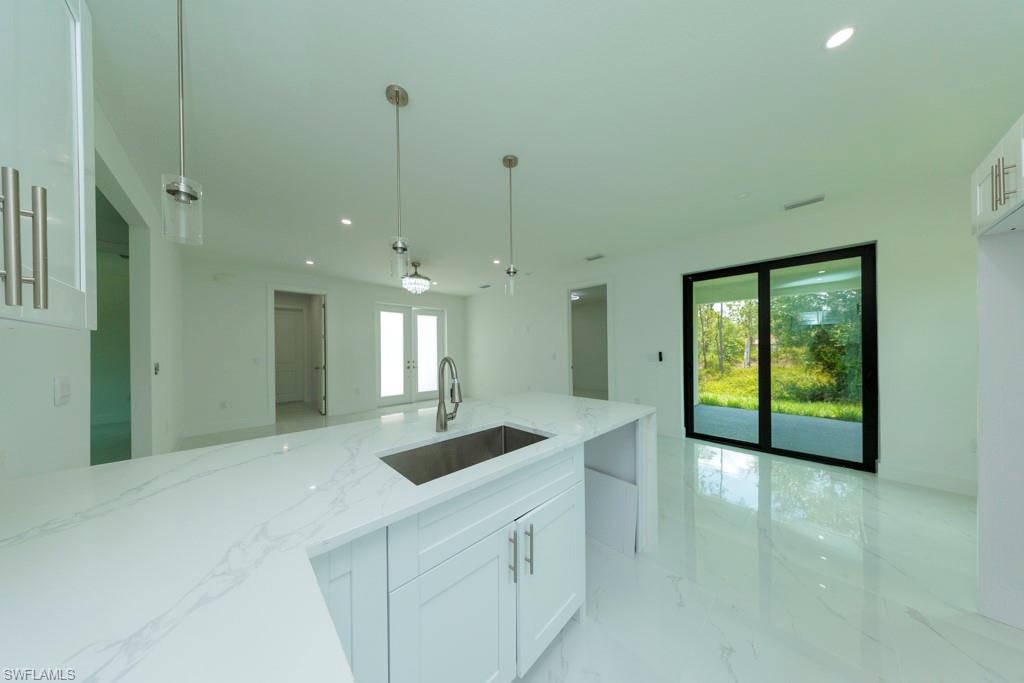 Kitchen island featuring a stainless steel undermount sink, gooseneck faucet, and white cabinetry