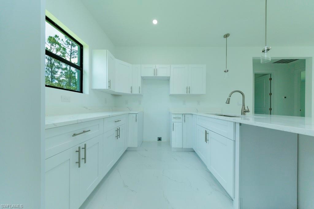 Modern kitchen featuring white shaker cabinetry, light-toned countertops, and a stainless steel pull-down faucet