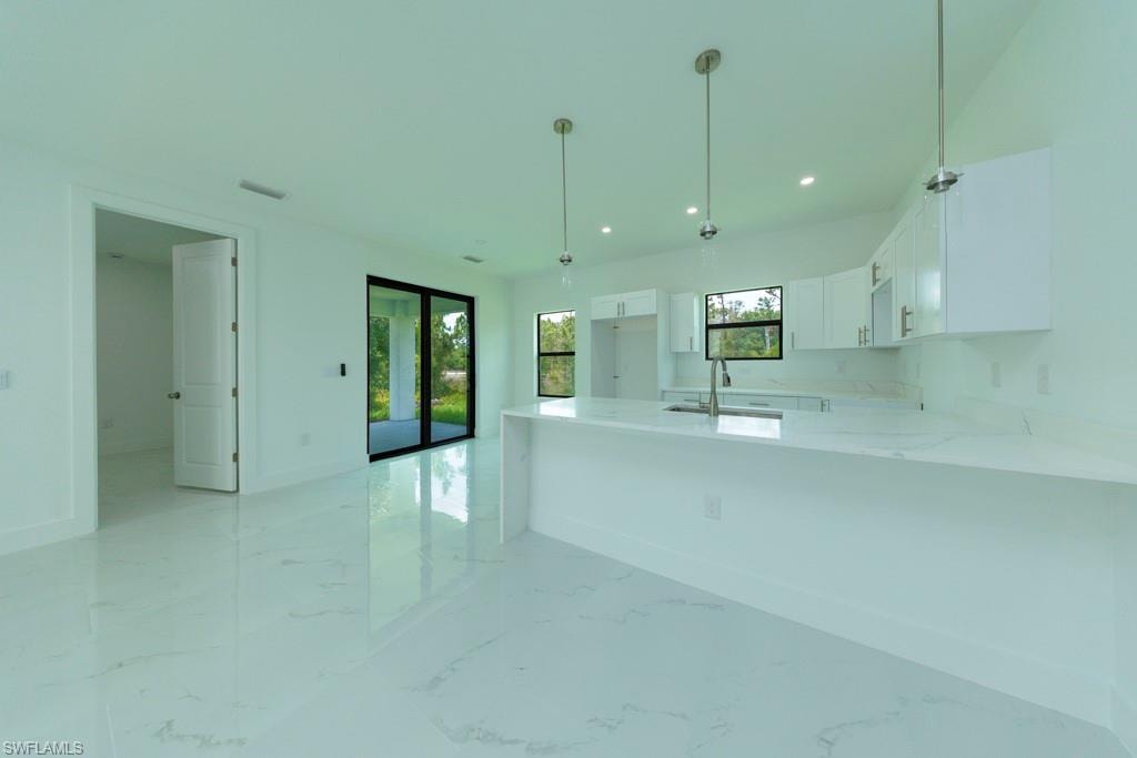 Modern kitchen featuring white cabinetry, a large kitchen island with a white countertop, and recessed lighting
