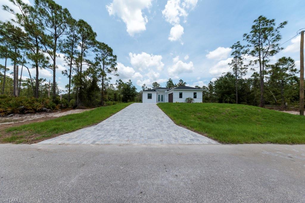 Modern white exterior with a dark roofline set against a backdrop of mature trees