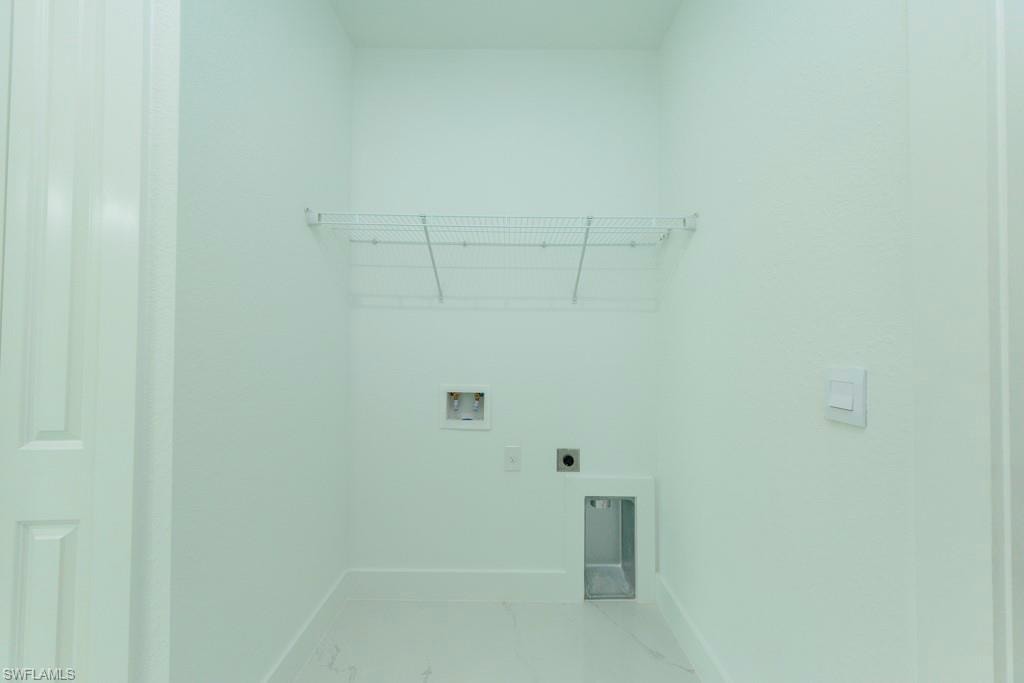Utility space featuring white walls, white trim, white flooring, and a wire storage shelf