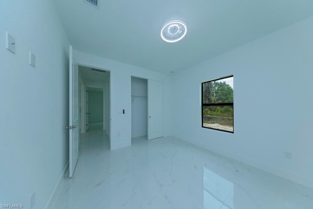 Bright interior room featuring white walls and large format tile flooring