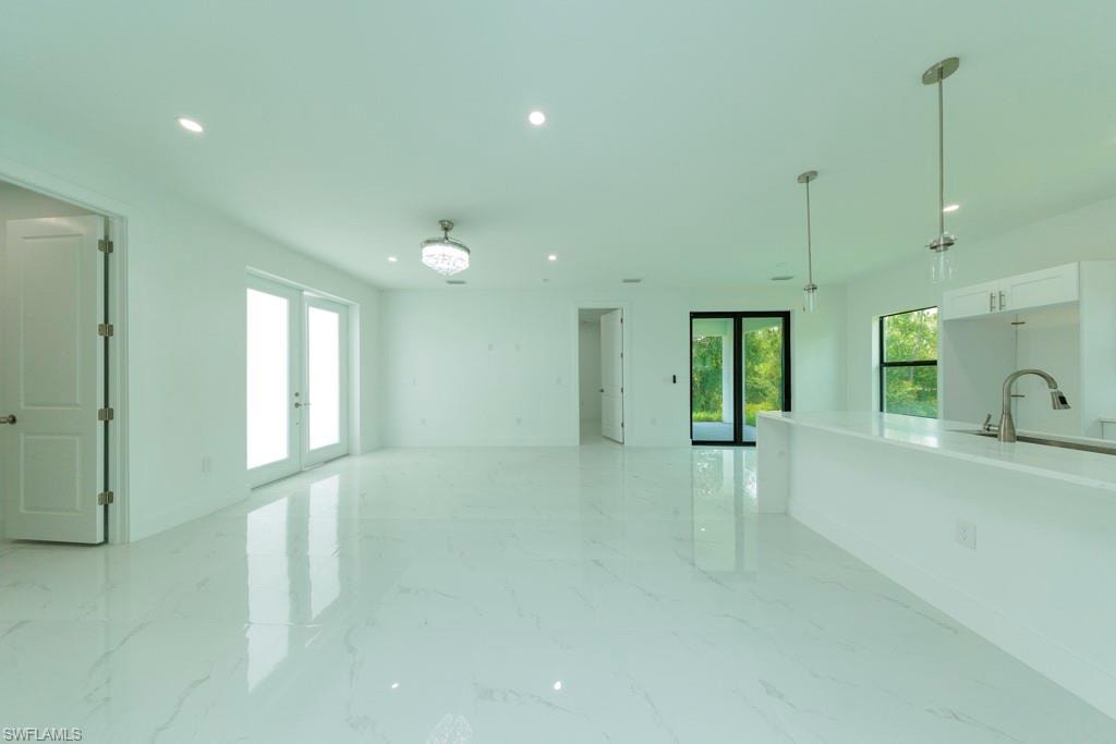 Spacious open-concept interior featuring large format marble-look tile flooring, recessed lighting, and a crystal chandelier