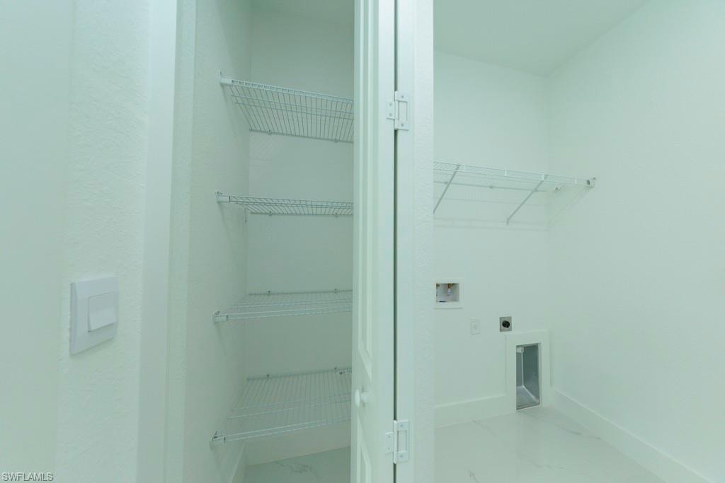 Utility room with wire shelving, wall-mounted outlets, and a floor vent