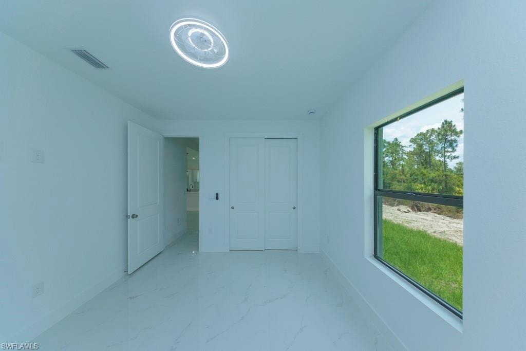 Light-filled interior space featuring a single window, white walls, and large format white tile flooring