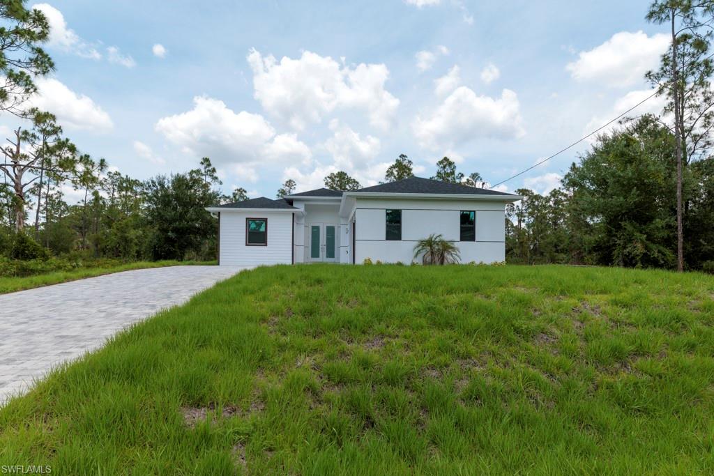 Contemporary single-story residence with a dark shingle roof, white exterior siding, and a paver driveway