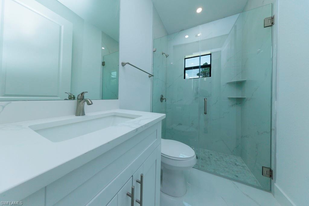 Contemporary bathroom featuring a frameless glass shower enclosure, a single vanity with an integrated sink, a large wall mirror, and recessed lighting