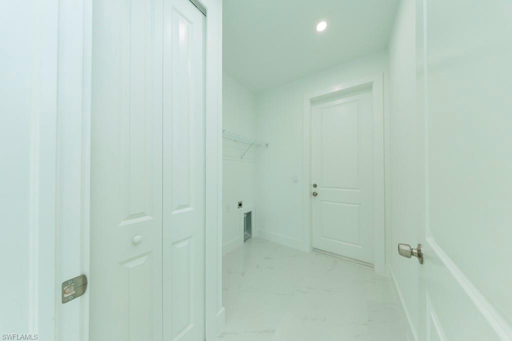 Utility room featuring white walls, white paneled doors, recessed lighting, and tile flooring