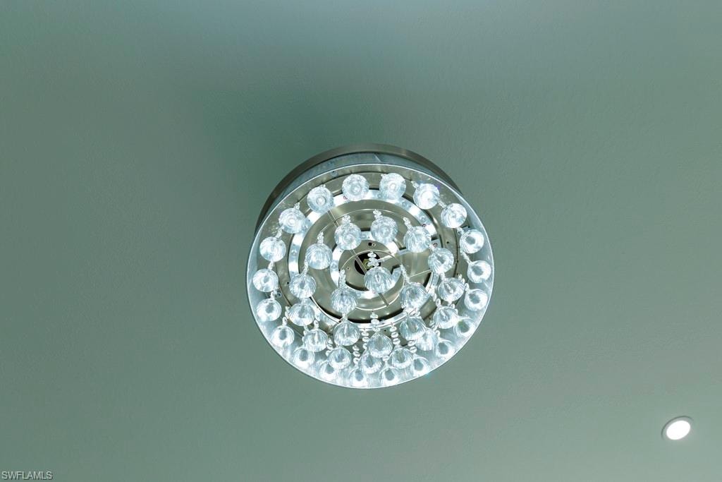 Recessed crystal chandelier featuring multiple tiers of faceted glass elements and a chrome-finish base, complemented by a single recessed ceiling light fixture
