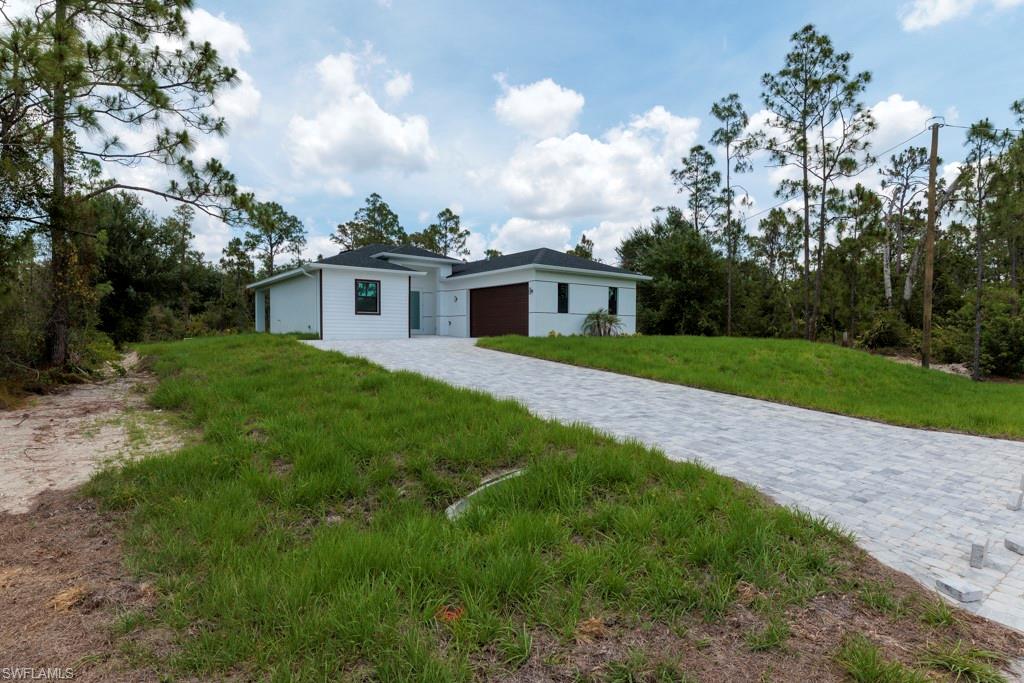 Contemporary white exterior with a dark roof and a paver driveway