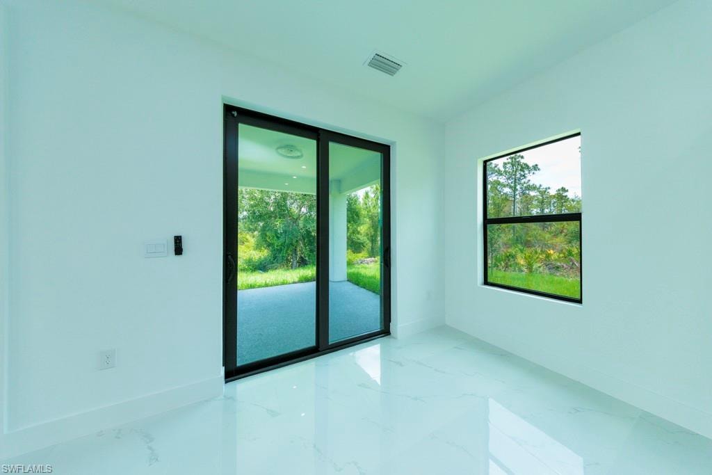 Spacious interior featuring white walls, white-finish flooring, a large sliding glass door, and a single-pane window