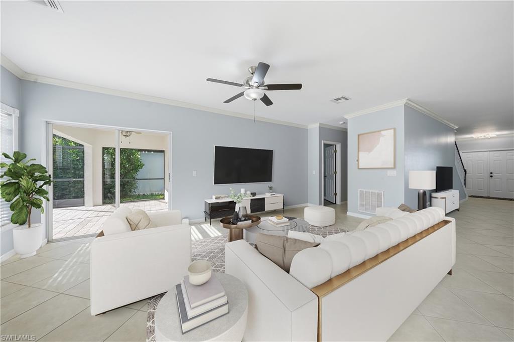 Spacious living area featuring light-toned tile flooring, light blue walls, and white crown molding