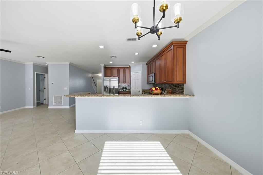 Open-concept living space featuring a kitchen with wood cabinetry, stainless steel appliances, and a stone countertop