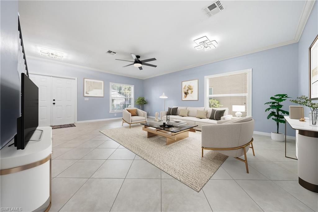 Spacious living area featuring light-toned tile flooring, light blue walls, and white crown molding