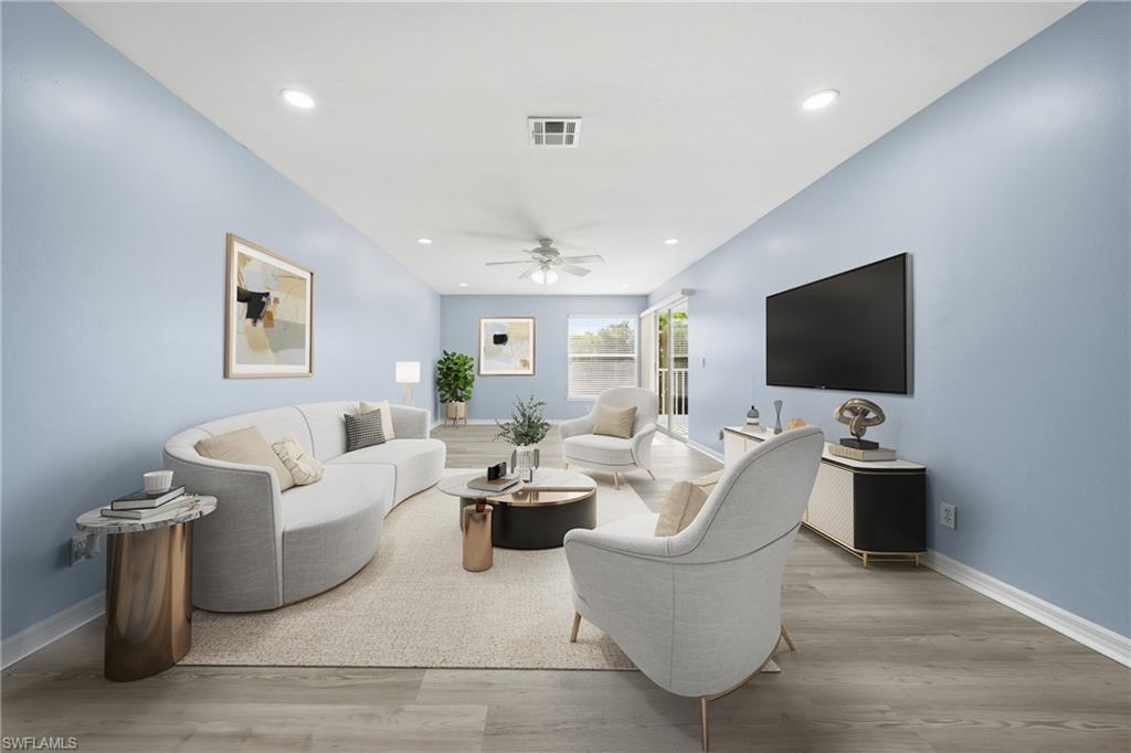 Spacious living area featuring light blue walls, recessed lighting, and wood-finish flooring