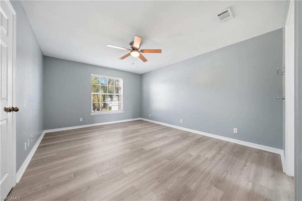 Spacious room featuring wood-finish flooring and a ceiling fan with integrated lighting
