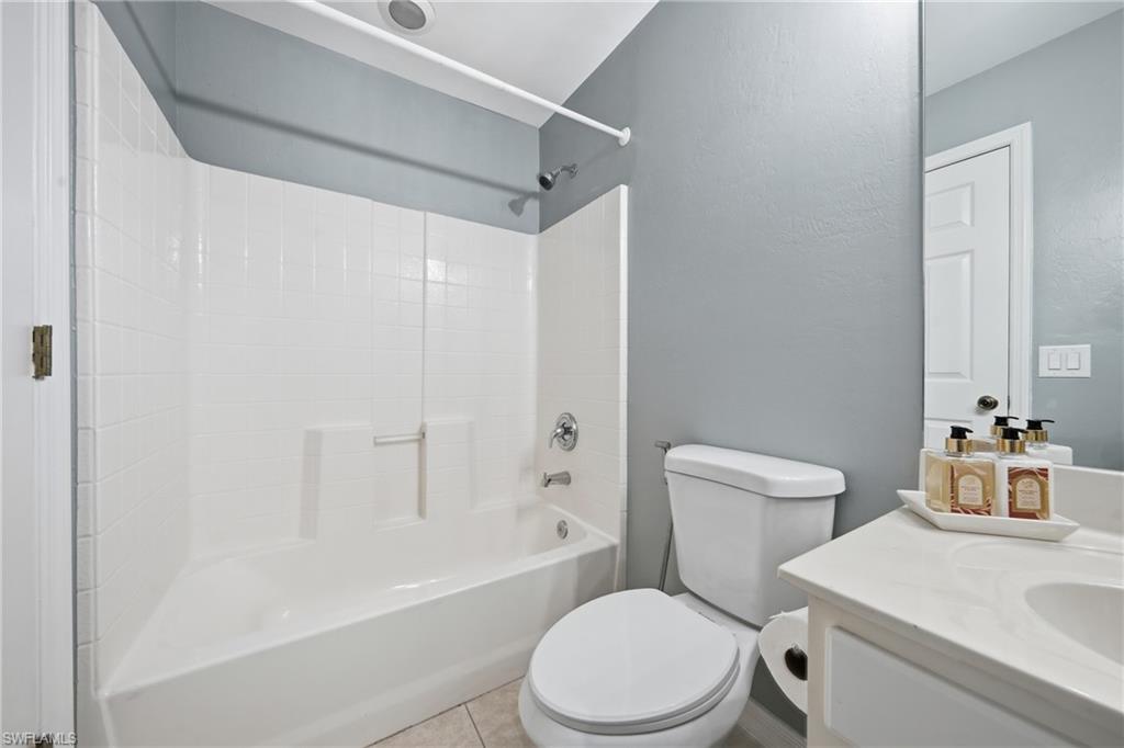 Full bathroom featuring a white tub/shower combination, white toilet, and a white single-sink vanity with an integrated countertop