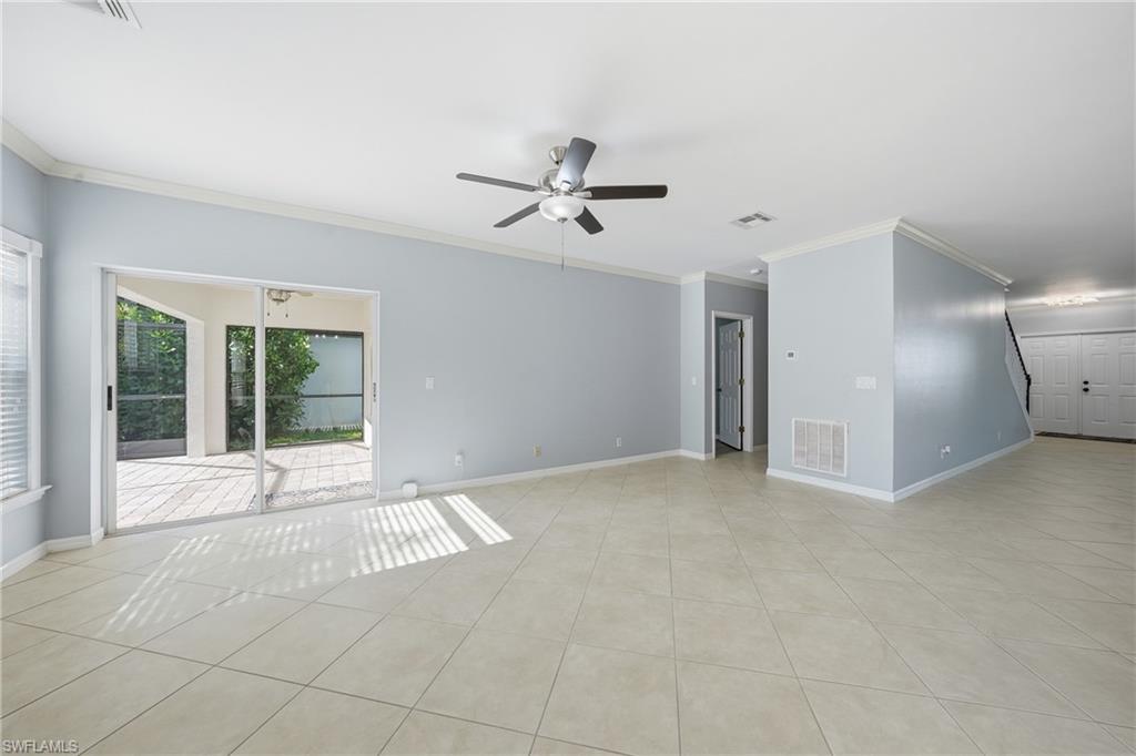 Spacious interior featuring neutral tile flooring, light blue wall paint, and white crown molding