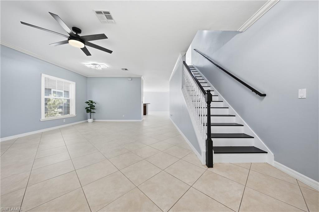 Spacious room featuring neutral tile flooring, light blue wall paint, and white baseboards